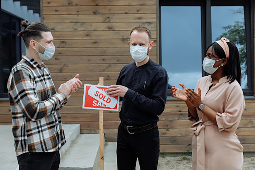 Three People Clapping Next To Sign